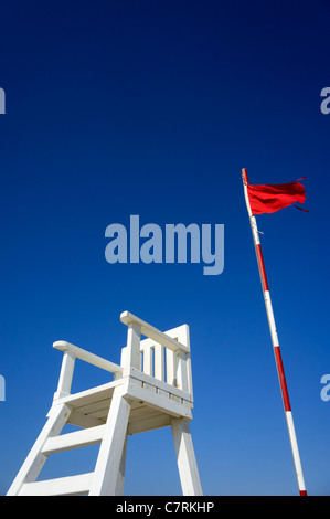 Rote Flagge am Strand Warnung nicht ins Wasser neben der Rettungsschwimmer Stuhl Stockfoto