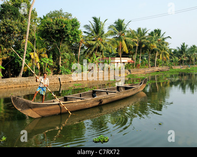 Mann stampfend sein leeres Arbeit Kanu, ein Vallam, entlang einem Fluß in den Hinterwässern von Kerala, Südindien, Indien Stockfoto
