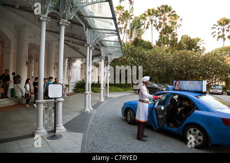 Der Doorman öffnet die Tür zu einem Taxi, Raffles Hotel, Singapur Stockfoto