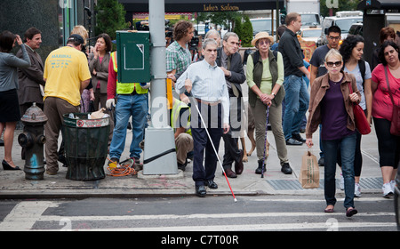 Sehbehinderte Fußgänger überqueren Sie die Kreuzung der Seventh Avenue und West 23rd Street im Stadtteil Chelsea in New York Stockfoto