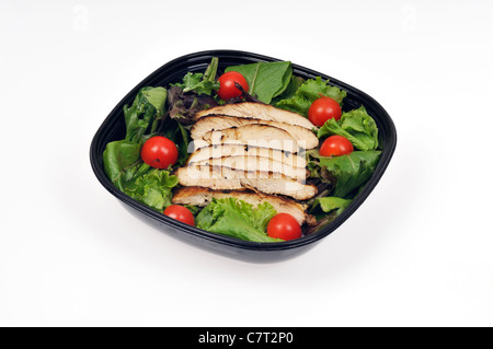 Streifen von gegrilltem Hähnchen auf einem Bett von Salat und Kirschtomaten in einem Salat in schwarzen Behälter auf weißem Hintergrund Ausschnitt. Stockfoto