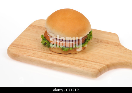 Chicken Burger mit Salat und Tomate auf ein Brot Rollen auf ein Holz Schneidebrett auf weißem Hintergrund Ausschnitt. Stockfoto