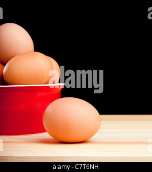 Eiern in eine Schüssel geben und eine auf der Bank, die isoliert auf schwarz Stockfoto