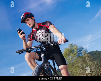 sportlichen Aktivität: junge Erwachsene Radsportler, Mountainbike und SMS auf Handy. niedrigen Winkel Ansicht Stockfoto