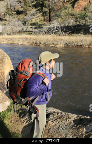 Seitenansicht der Frau Backpacker auf einem Felsen am Fluss Stockfoto