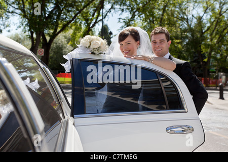 Glückliches Hochzeitspaar in Auto bekommen und Blick in die Kamera Stockfoto