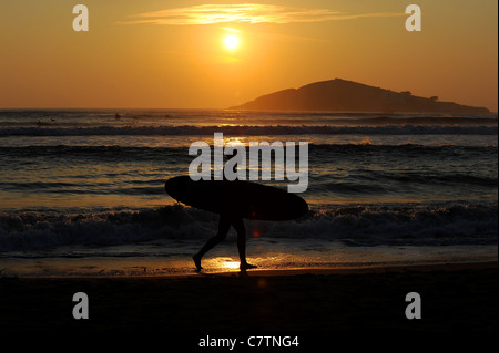 Eine Surfer Spaziergänge Größe Strand in Devon bei Sonnenuntergang im späten September Stockfoto