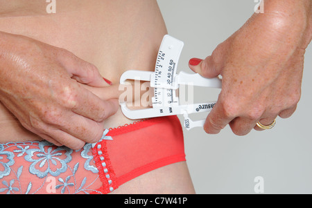 Mittleren Alters verteilt Frau Überprüfung ihrer Fettmessung Stockfoto