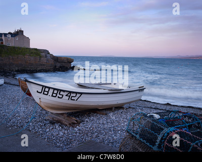 Boote am Strand in der Abenddämmerung in Anglesey North Wales mit Sonnenuntergang. Stockfoto