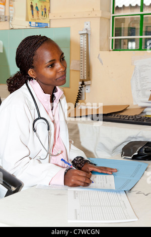 Ärztin schreibt Patientennotizen an einem Schreibtisch im Marangu Hospital, Moshi, Tansania. Stockfoto