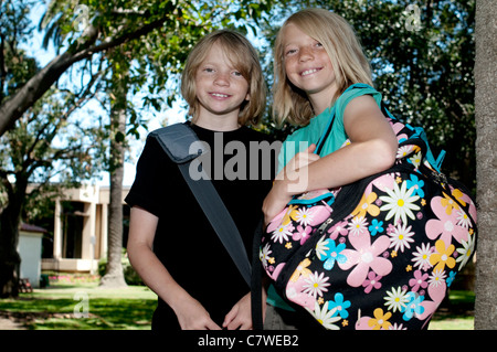 Zwei elementare Alter Kinder mit Rucksäcken auf dem Schulhof. Stockfoto