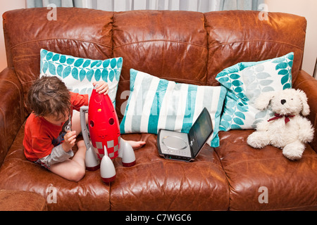 Vier Jahre alter Junge sitzt auf dem Sofa spielen mit einem Spielzeug-Rakete Stockfoto