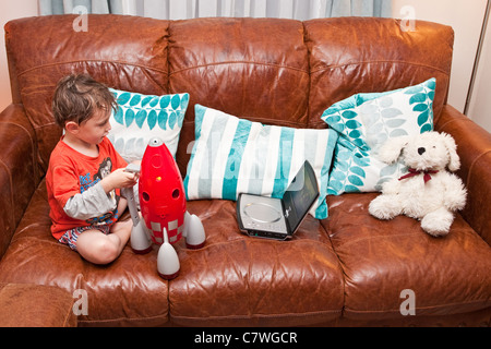 Vier Jahre alter Junge sitzt auf dem Sofa spielen mit einem Spielzeug-Rakete Stockfoto