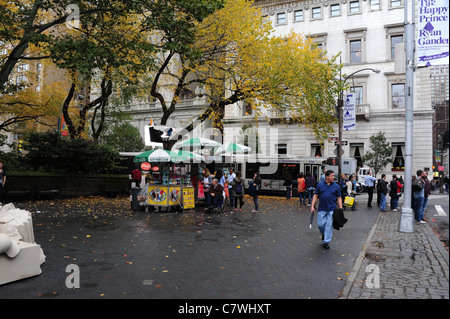 Nasse Wetter Blick herbstliche Bäume, Menschen, Imbiss-Stände, breiten Bürgersteig, Doris C. Freedman Plaza, Central Park South, New York Stockfoto