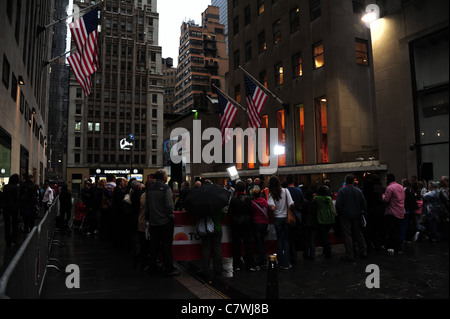 Am frühen Morgen Menschenmenge beobachten "Today Show" unter amerikanischen Flaggen, NBC News Studios, nass Fussböden Rockefeller Plaza in New York City Stockfoto