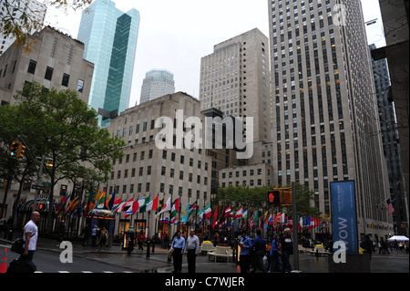 Nassen Herbst Blick von West 50th Street, multi-nationalen Flaggen, Menschen, graue Hochhäuser, Rockefeller Plaza, Manhattan, New York Stockfoto