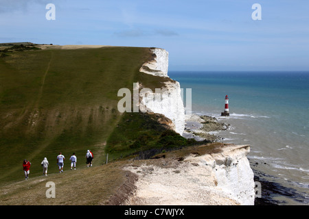 Wanderer zu Fuß entlang der South Downs Way Küste Weg, Beachy Head Leuchtturm im Hintergrund, in der Nähe von Eastbourne, East Sussex, England Stockfoto