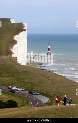 Menschen zu Fuß entlang der Küstenweg, Beachy Head Leuchtturm im Hintergrund, in der Nähe von Eastbourne, East Sussex, England Stockfoto