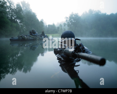 Spezielle Operationen Kräfte bekämpfen Taucher Transite das Wasser mit einem Sturmgewehr bewaffnet. Stockfoto