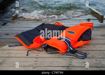 Verlassene, rote Rettungsweste für Wassersportler, die auf eine Bootsrampe geworfen Stockfoto