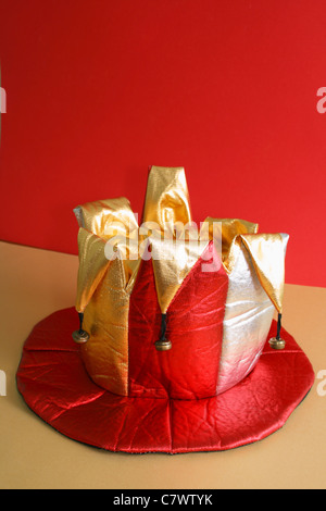 Gold Jesters Hut hat den roten Hintergrund Stockfoto