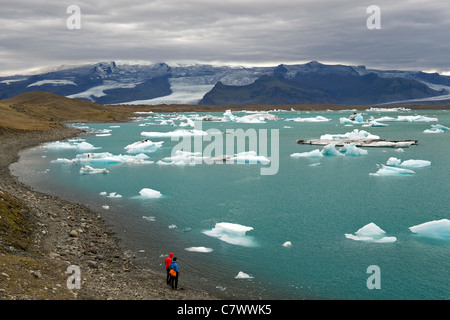 Touristen, die Eisberge schwimmen im Jokullsarlon-See am Fuße des massiven Vatnajökull-Gletscher im Südosten Islands beobachten. Stockfoto