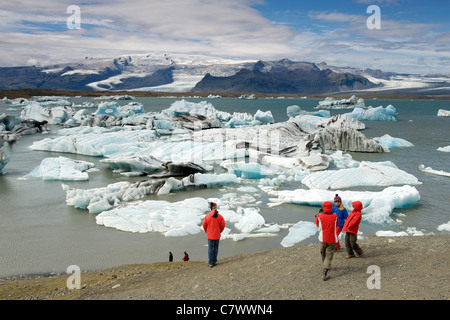 Touristen, die Eisberge schwimmen im Jokullsarlon-See am Fuße des massiven Vatnajökull-Gletscher im Südosten Islands beobachten. Stockfoto