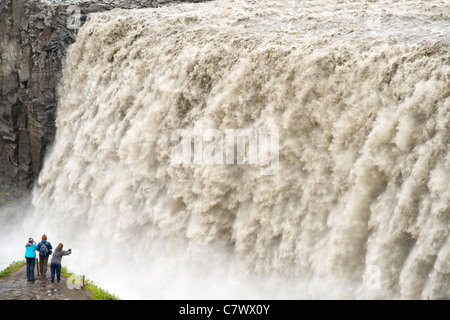 Touristen am Dettifoss-Wasserfall am Fluss Jökulsá Á Fjöllum in der Nähe von Myvatn im Vatnajökull-Nationalpark, Nordosten Islands. Stockfoto