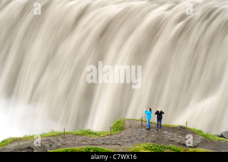 Touristen am Dettifoss-Wasserfall am Fluss Jökulsá Á Fjöllum in der Nähe von Myvatn im Vatnajökull-Nationalpark, Nordosten Islands. Stockfoto