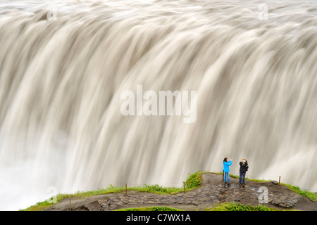 Touristen am Dettifoss-Wasserfall am Fluss Jökulsá Á Fjöllum in der Nähe von Myvatn im Vatnajökull-Nationalpark, Nordosten Islands. Stockfoto