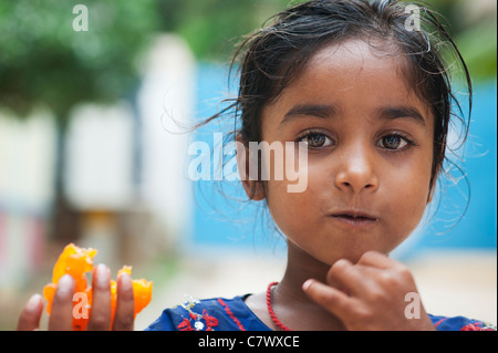 Armen niedrigere Kaste indischen Straße Mädchen halten und eine traditionelle indische süß zu essen. Jaangiri / Jangiri / Imarti. Selektiven Fokus. Stockfoto