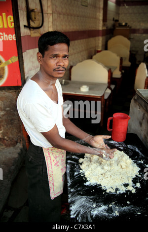 Porträt der indischen Jüngling Mischung aus Mehl und Wasser auf große Teller im kleinen Restaurant in Hyderabad Indien. Stockfoto