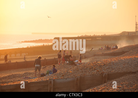 Brighton und Hove direkt am Meer in der Abenddämmerung, mit Menschen mit Grill am Strand Stockfoto