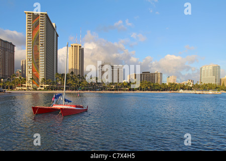 Roten Katamaran und mehrere Hotels entlang Fort DeRussy Beach in der Nähe von Waikiki bilden eine partielle Skyline von Honolulu, Hawaii Stockfoto
