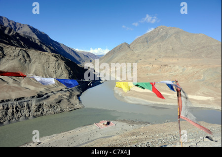 Gebetsfahnen markieren den Zusammenfluss des Flusses Zanskar und Indus in der Nähe von Nimu. Indus kommt von der linken Seite. Stockfoto