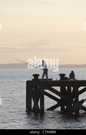 Angeln im Firth of Clyde am Portencross Pier bei Sonnenuntergang, North Ayrshire, Schottland, Großbritannien Stockfoto