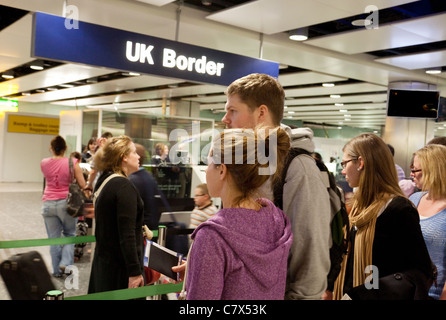 Junge Menschen warten in einer Schlange, um die britische Grenze bei der Einwanderungsppasskontrolle, Terminal 3, Heathrow Airport, London England zu betreten Stockfoto