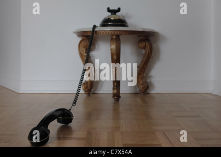 im Vordergrund sehen wir den Telefonhörer, Hintergrund: eine kleine, klassische Tisch, gegen die Wand Stockfoto