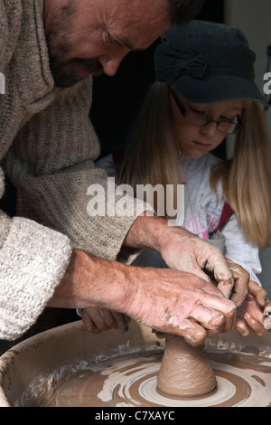 Ein Töpfer und Mädchen prägen ein Stück Keramik auf eine elektrisch angetriebene Töpferscheibe auf Workshops unter Lielupes Ikskile Lettland Stockfoto