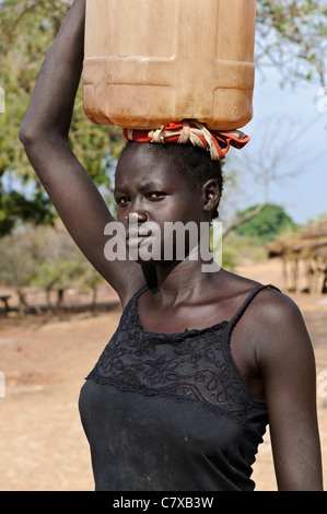Ein junges Mädchen mit einem Wasserbehälter wieder aus dem Bohrloch, Luonyaker, Bahr El Ghazal, Süd-Sudan. Stockfoto