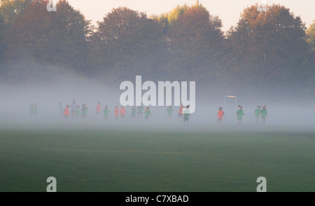 Schulkinder laufen am nebligen Morgen, Wandsworth Common, London UK Stockfoto