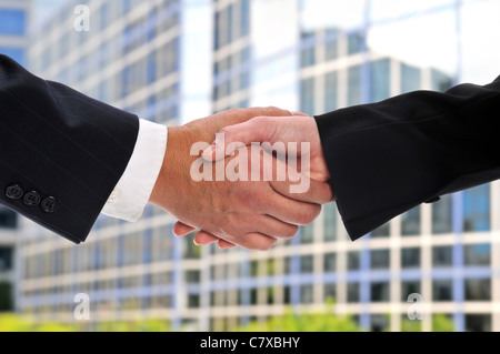 Handschlag zwischen Unternehmer und eine Geschäftsfrau mit dem Bau auf dem Hintergrund Stockfoto