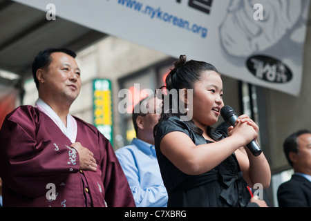 Junges Mädchen singt die Nationalhymne auf der Bühne in Koreatown auf West 32nd Street in New York auf einer Straße Messe Stockfoto