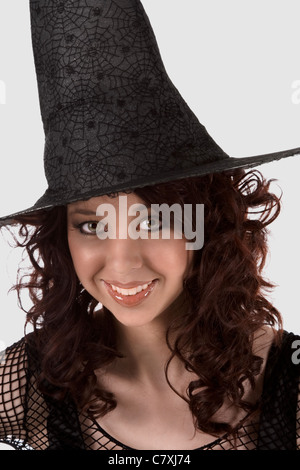 Porträt von Hispanic Teenager Mädchen in schwarz Halloween Hut und Netzstrümpfe Kleid Stockfoto