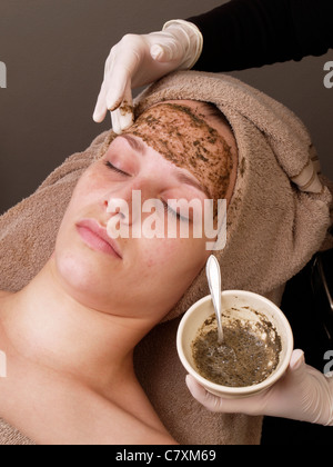 Frau mit Augen geschlossen, während chinesische Peeling Maske von Kräuter-Algen und Seegras im Gesicht angewendet wird Stockfoto