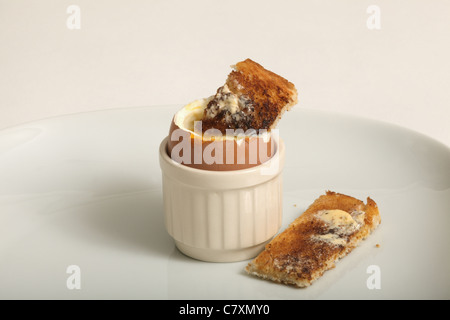 Ein Toast "Soldier" tauchte in ein weich gekochtes Ei auf einem weißen Teller Stockfoto