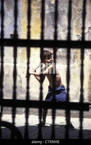 Kuba, Santiago De Cuba: Junge spielt auf der Straße hinter einem Zaun Stockfoto