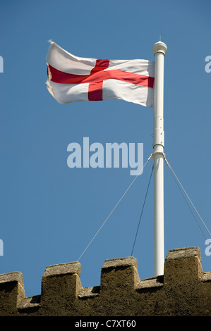 Das Kreuz von St. George Flag fliegt von einem kirchlichen Fahnenmast vor blauem Himmel. Stockfoto