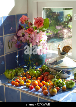 REIFE TOMATEN UND BLUMEN AUF DER FENSTERBANK IN DER KÜCHE UK Stockfoto