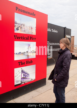 Eine Frau schaut ein Rat Anzeige vorgeschlagenen neuen Strandpromenade Entwicklungen in Redcar Cleveland UK 2011 Stockfoto